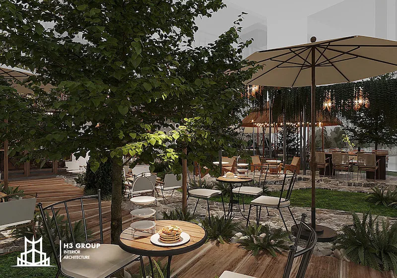 Mẫu thiết kế cafe Vintage sân vườn về đêm đầy lãng mạn với ánh đèn vàng kết hợp tán cây xanh tạo nên không gian ngoài trời yên tĩnh và thư giãn