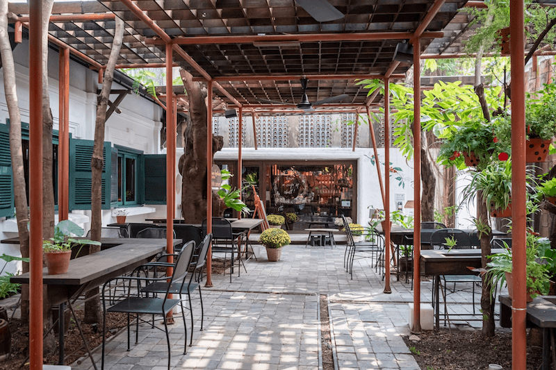 Mẫu thiết kế quán cafe 1 tầng với không gian sân vườn thoáng đãng, xanh mát với mái che và bàn ghế tối giản