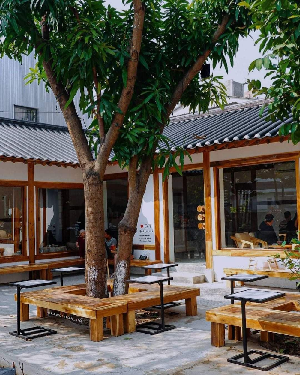 Kiến trúc gỗ mộc mạc, mái ngói đặc trưng kiểu Nhật, bàn ghế tối giản bao quanh gốc cây xanh tạo nên không gian quán cà phê sân vườn gần gũi