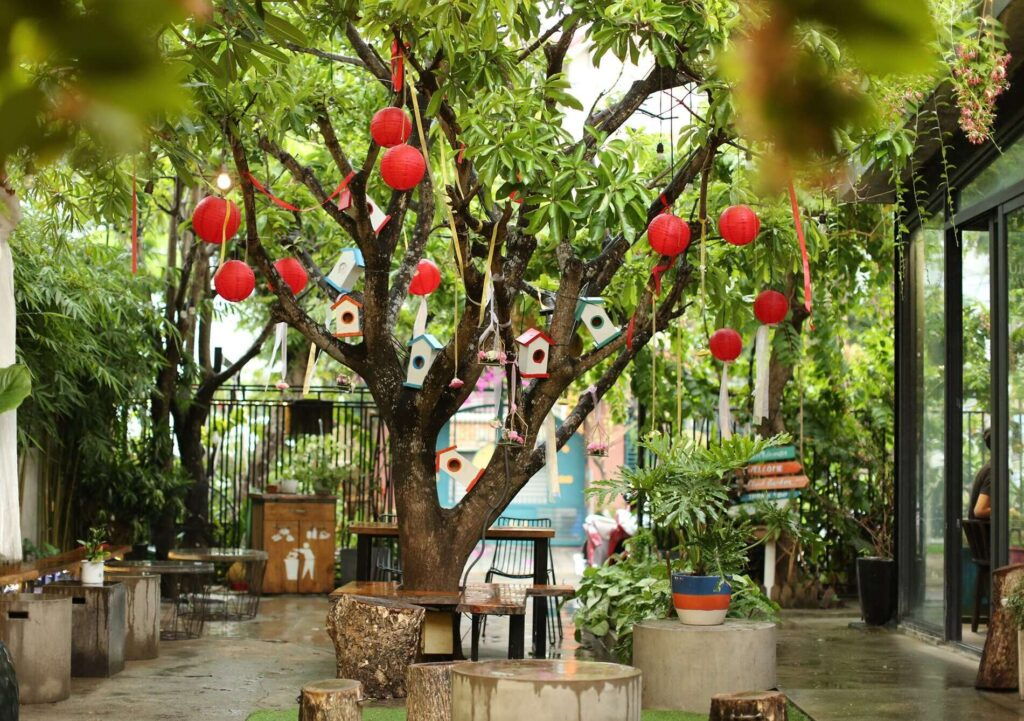 Quán cà phê sân vườn phong cách Việt Nam với bàn đá, ghế gỗ, lồng đèn đỏ và bờ tre nhỏ gợi nhớ đến khung cảnh làng quê mộc mạc, bình yên