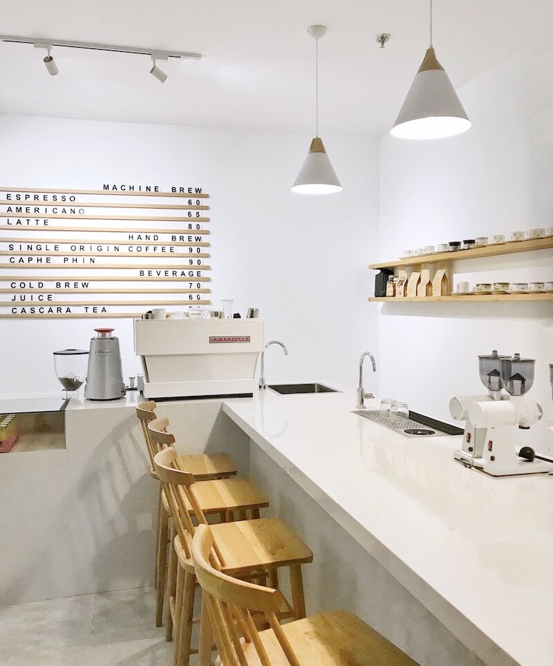 Với phong cách tối giản trên nền trắng chủ đạo, kết hợp cùng điểm nhấn gỗ mộc và chi tiết trang trí như bảng menu ghép chữ thông minh, tạo nên không gian quán đầy ấn tượng, giúp chủ đầu tư tối ưu chi phí
