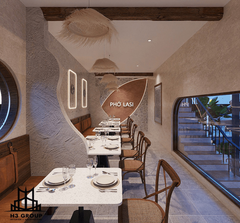 Bàn đá sáng màu, tường có texture nhẹ và mặt kính lớn bên phải giúp phản chiếu ánh sáng tốt hơn, khiến không gian nhà hàng như rộng và thoáng hơn