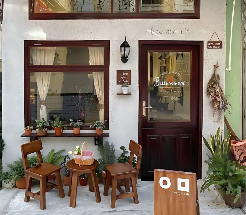 Quán cafe Châu Âu cổ điển nổi bật với mặt tiền xanh lá cây và bàn ghế vỉa hè Parisian đặc trưng