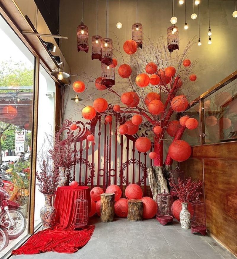 Quán cà phê được trang trí dịp Tết với góc check-in nổi bật bởi những chiếc lồng đèn đỏ rực rỡ và cành nụ tầm xuân đỏ, mang đến không khí sum vầy, may mắn và tràn đầy sức sống 