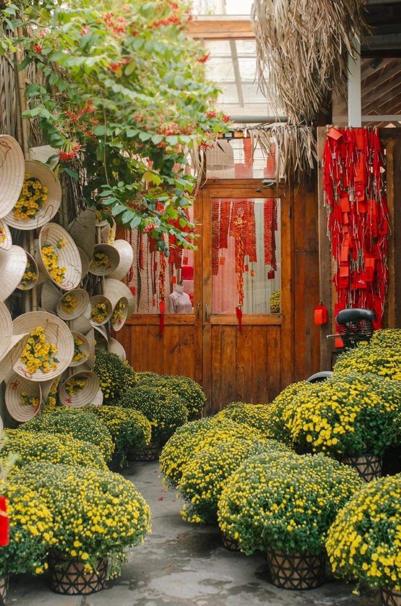 Quán cà phê được trang trí rực rỡ dịp Tết với góc check-in nổi bật bao lì xì đỏ, dây pháo truyền thống và chậu cúc mâm xôi vàng, tạo không gian tràn ngập sắc xuân