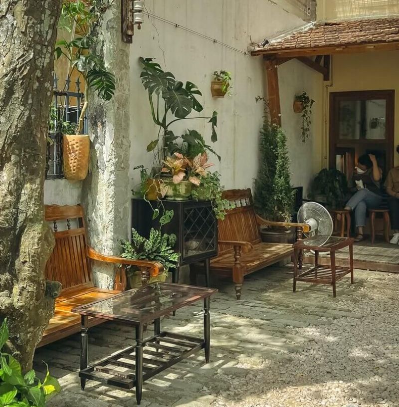 Quán cà phê mang phong cách Vintage với không gian sân vườn mộc mạc, bàn ghế gỗ xưa và nhiều cây xanh. Sự kết hợp này tạo nên cảm giác hoài cổ, gần gũi, thích hợp để thư giãn