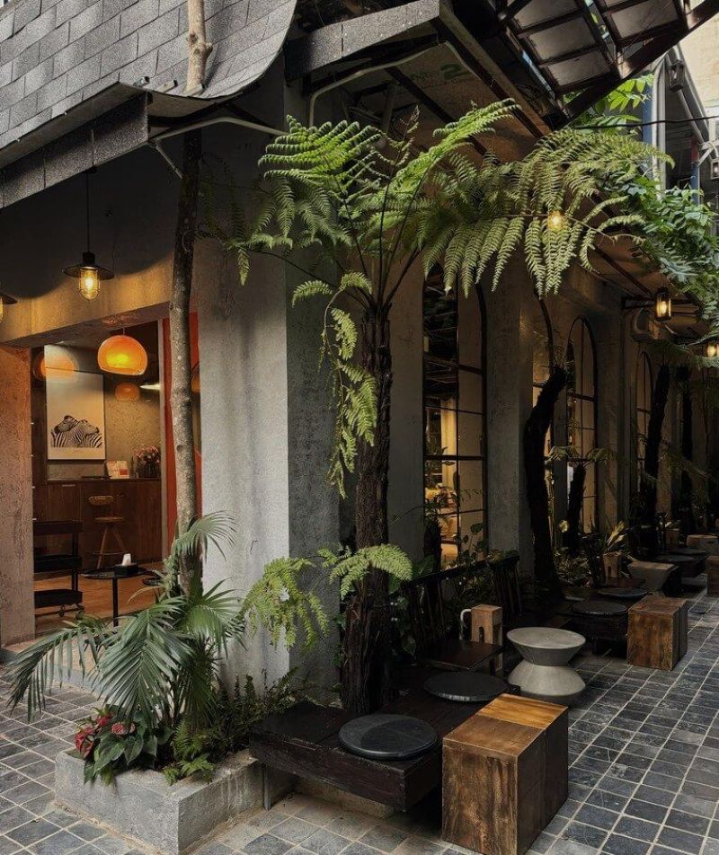Quán cà phê mang phong cách Vintage, sử dụng vật liệu thô như xi măng và đá tự nhiên, kết hợp cây xanh và nội thất gỗ, tạo nên một không gian hoài cổ, nhẹ nhàng và thư thái
