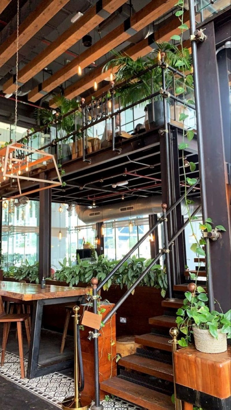 Quán cafe khung thép 2 tầng phong cách Tropical tạo cảm giác gần gũi thiên nhiên với cây xanh được bố trí xuyên tầng và bao quanh không gian 