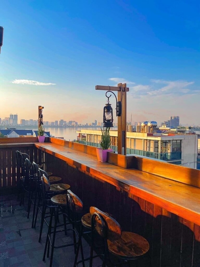Quán cafe rooftop hiện đại kết hợp ánh sáng vàng ấm và nội thất đơn sắc, tạo bầu không khí ấm cúng về đêm