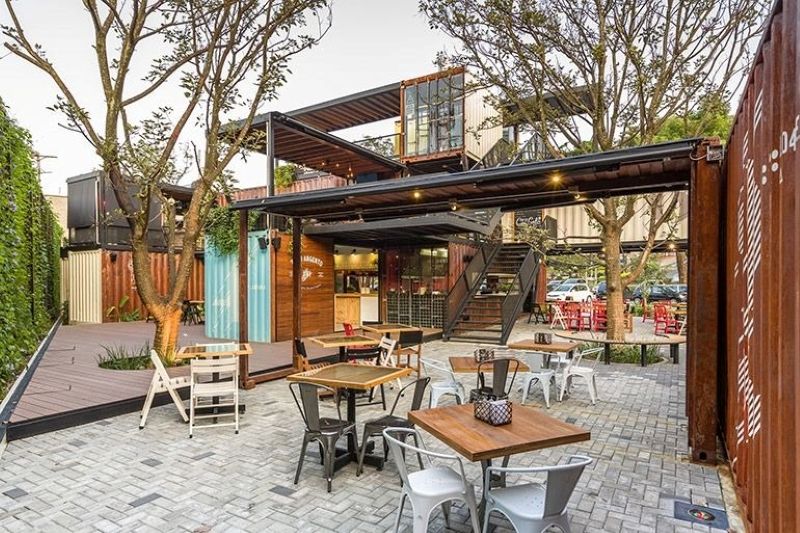 Quán cafe khung thép container 2 tầng trở nên nổi bật khi ứng dụng phong cách Tropical với màu sắc và cây xanh tươi mát 