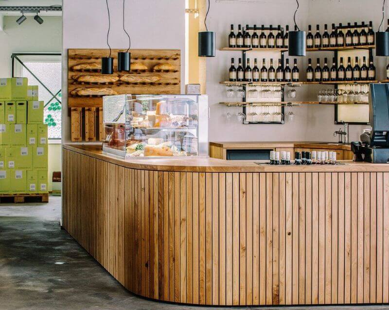 Quầy bar được ốp bằng các tấm gỗ tần bì ghép dọc, với tông nâu trung bình, vân gỗ rõ nét và bề mặt hoàn thiện tỉ mỉ, tạo nên tổng thể hài hòa và tinh tế  