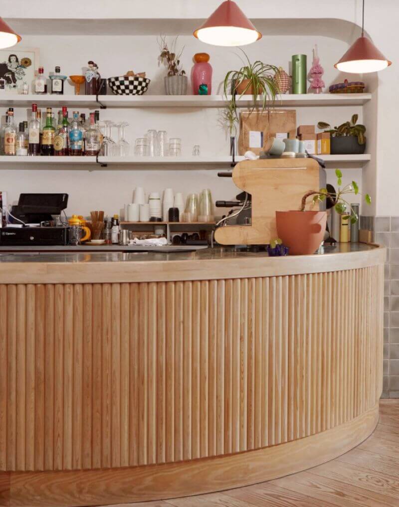 Gỗ với tông màu sáng tự nhiên, kết hợp thiết kế thanh sọc dọc đều đặn và đường cong mềm mại, tạo nên quầy bar mang vẻ ngoài tinh tế, nhẹ nhàng và hiện đại  