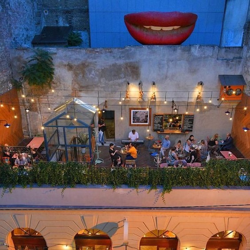 Thiết kế cafe sân thượng Industrial kết hợp ánh sáng vàng ấm để làm mềm đi sự lạnh lẽo của vật liệu thô