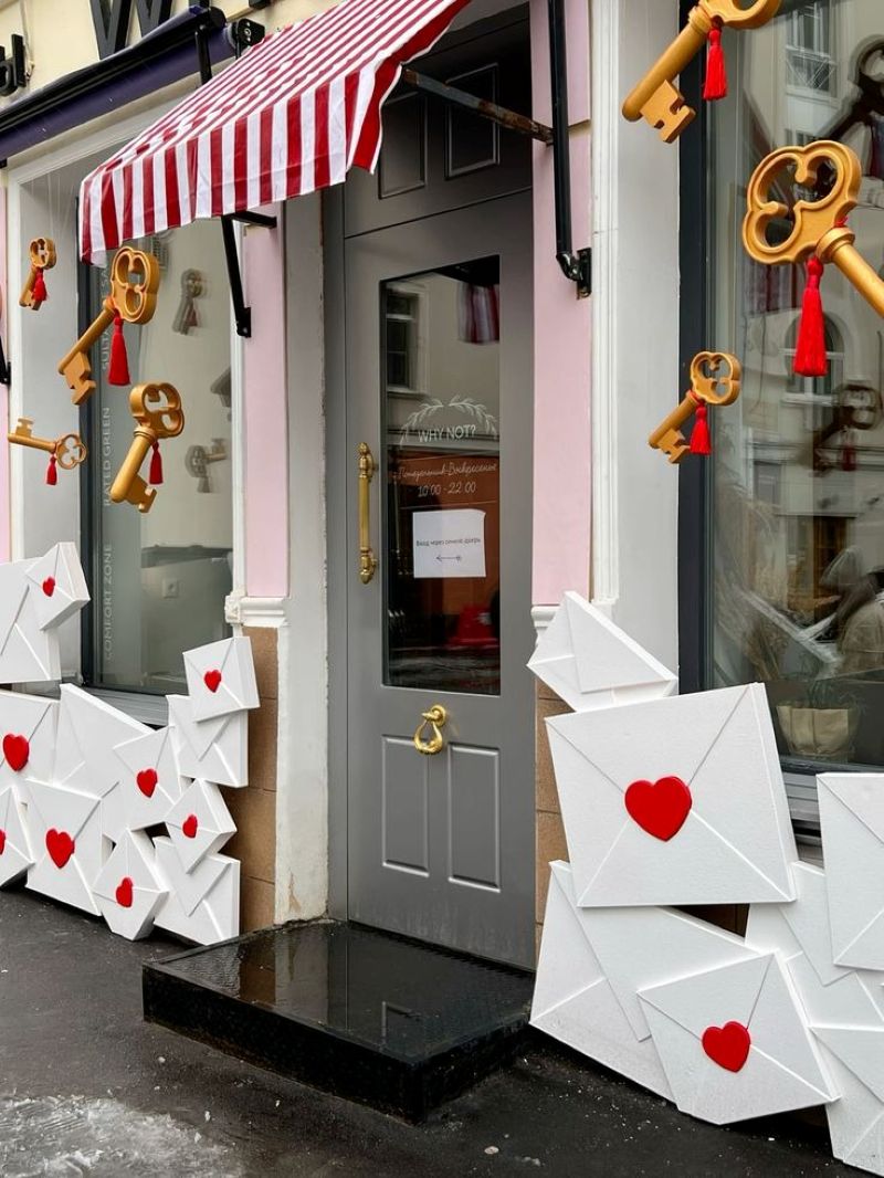 Quán cà phê được trang trí bằng những chiếc thư cổ điển treo trái tim đỏ và các phong bì trắng nâu, kèm theo cánh cửa và mái che đỏ - trắng, tạo nên không khí Valentine ấm áp và ngọt ngào