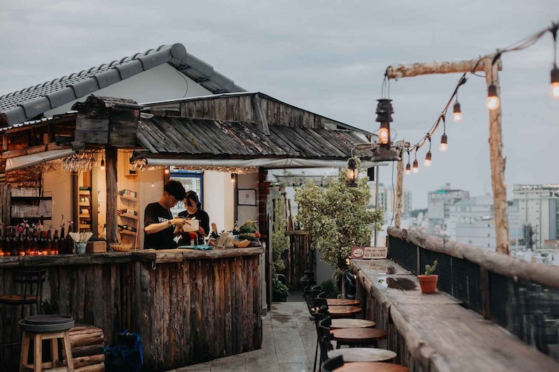 Quán cafe rooftop nổi bật với quầy bar ngoài trời, nơi thưởng thức đồ uống giữa không gian thoáng đãng và view thành phố