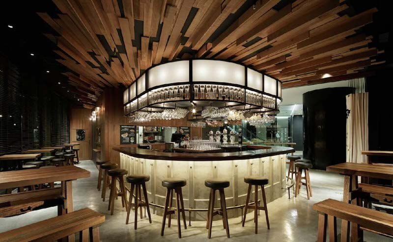 Thiết kế quầy bar sang trọng với trần gỗ nghệ thuật và hệ treo ly tinh tế, tạo điểm nhấn thị giác mạnh mẽ
