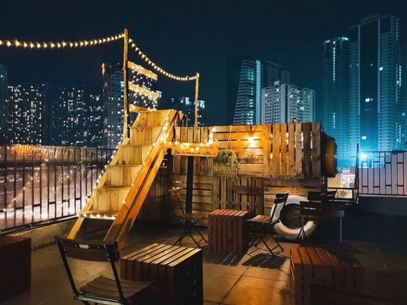 Quán cafe rooftop sử dụng ánh sáng vàng ấm áp quanh sân khấu acoustic, khiến không gian thêm phần lãng mạn, thu hút các cặp đôi