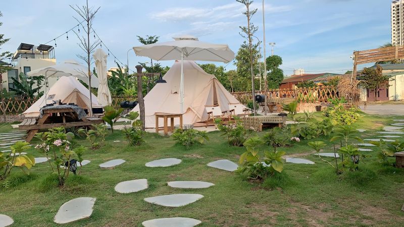 Cafe sân vườn cắm trại tái hiện lại không gian picnic với lều vải, bàn ghế gỗ và đèn dây nối dài, đây là lựa chọn hấp dẫn cho những dịp vui chơi cuối tuần