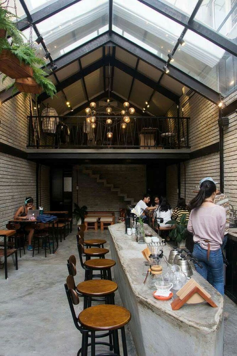 Quán cafe khung thép 2 tầng phong cách Industrial nổi bật với thiết kế lộ kết cấu, sử dụng vật liệu thô mộc như thép đen, bê tông trần và gạch thô không tô trát