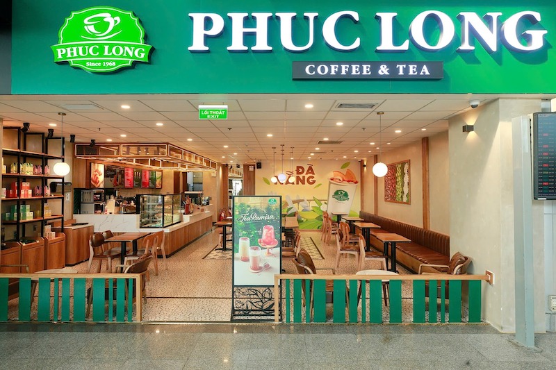 Phúc Long nổi bật với bàn gỗ nâu, tone màu xanh lá và quầy bar đá sáng màu , tất cả đều được chuẩn hóa ở các chi nhánh