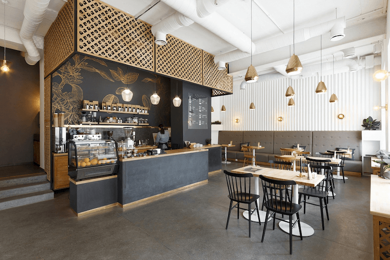 Mẫu thiết kế quán cafe Industrial kết hợp ánh sáng vàng và vật liệu thô tạo chiều sâu không gian