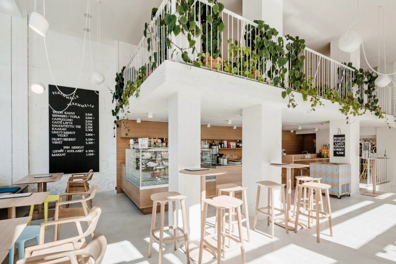 Quán cafe nổi bật với thiết kế gác lửng thanh thoát, trụ vuông trắng, lan can sắt mảnh, kết hợp ánh sáng tự nhiên và cây xanh tạo nên một không gian dịu mắt 