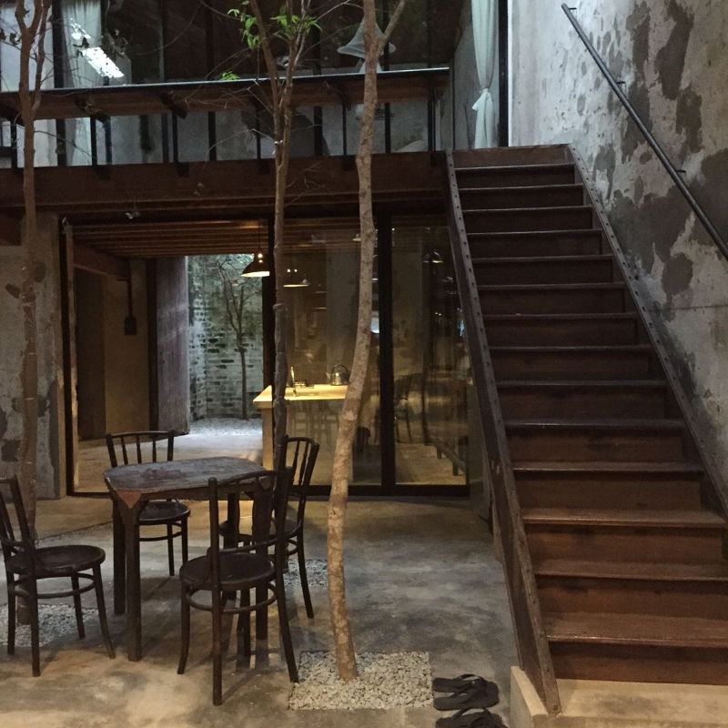 Không gian cafe gác lửng như bước ra từ một thước phim cũ với cầu thang gỗ, tường xi măng kết hợp một vài cây khô làm điểm nhấn nổi bật