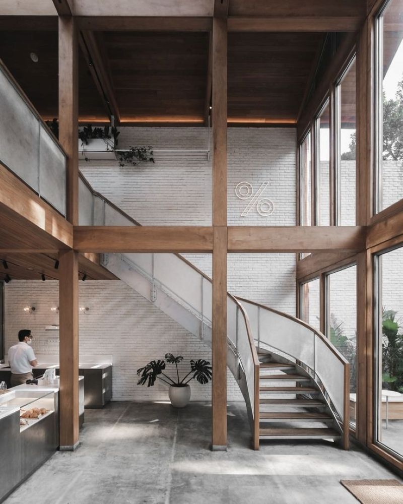 Quán cafe gác lửng nổi bật với trần cao, sử dụng kết cấu gỗ lớn và các mảng kính trong suốt tạo cảm giác thoáng đãng cho không gian 