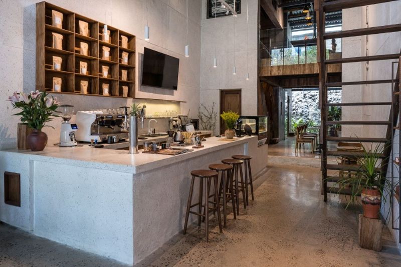 Thiết kế không gian quán cafe có gác lửng tối giản với sự kết hợp hài hòa giữa tone màu trắng xám chủ đạo và nâu trầm của cầu thang và bàn ghế gỗ