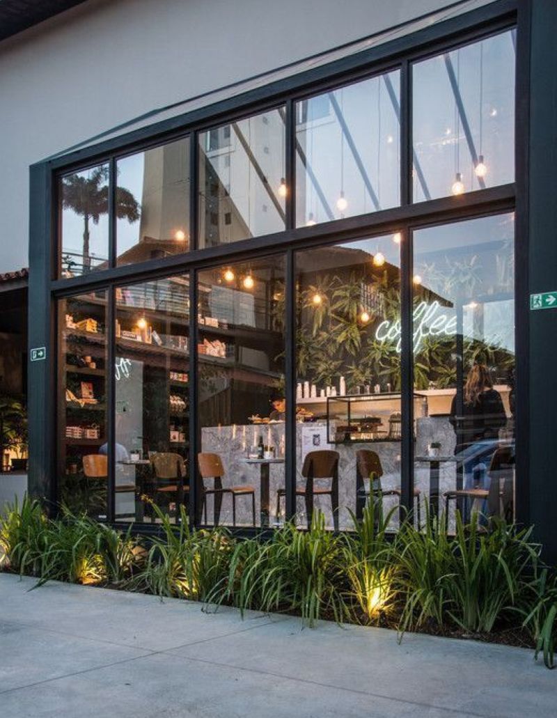 Không gian quán cafe hiện đại với tường kính trong suốt mang đến cảm giác thoáng đãng và tràn ngập ánh sáng tự nhiên