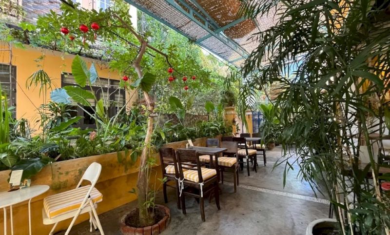 Quán cafe phong cách Hội An sử dụng bàn ghế gỗ mộc mạc, màn tre và lồng đèn đỏ nhỏ để tái hiện không gian giản dị, gần gũi của phố cổ