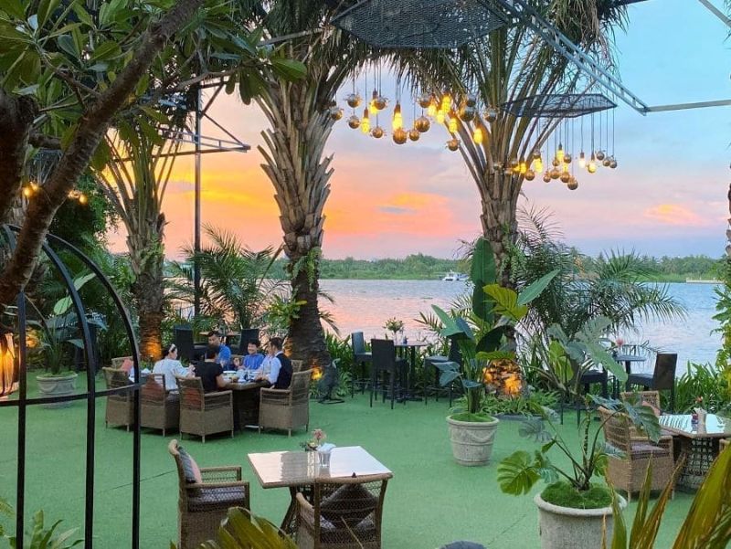 Quán cafe Tropical ven sông được bao phủ bởi mảng xanh tươi mát với những hàng dừa, cau cảnh và cây nhiệt đới trải dọc lối vào 