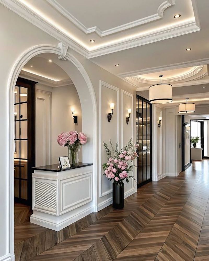 Để sảnh tân cổ điển nổi bật, hãy kết hợp bàn chạm khắc, lọ hoa nhỏ và ánh sáng vàng ấm đầy trang nhã