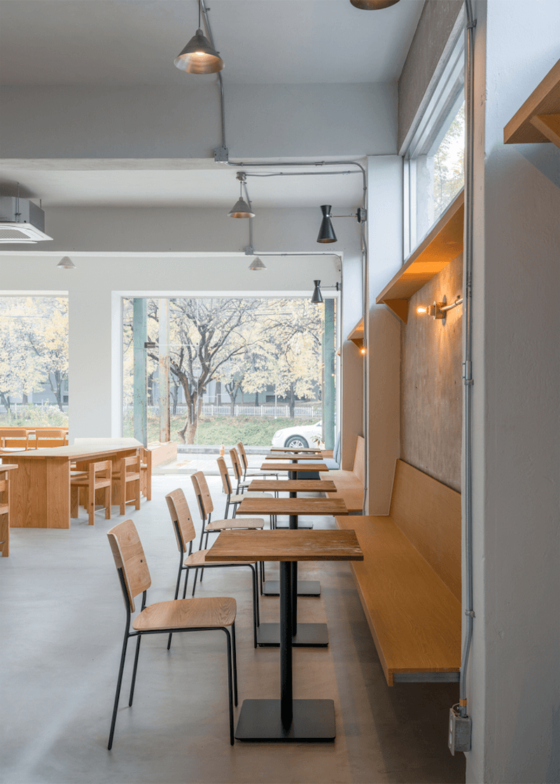 Vật liệu gỗ, kính và kim loại sơn tĩnh điện giúp quán cafe phong cách hiện đại tối giản vừa sang trọng vừa gần gũi