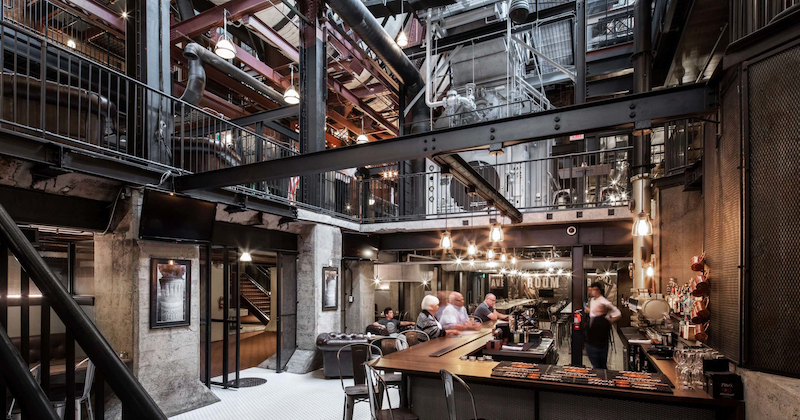 Thiết kế nhà hàng khung thép phong cách Industrial lộ kết cấu thép, trần cao và ống dẫn kỹ thuật, tạo không gian mở mạnh mẽ và ấn tượng cho khách hàng