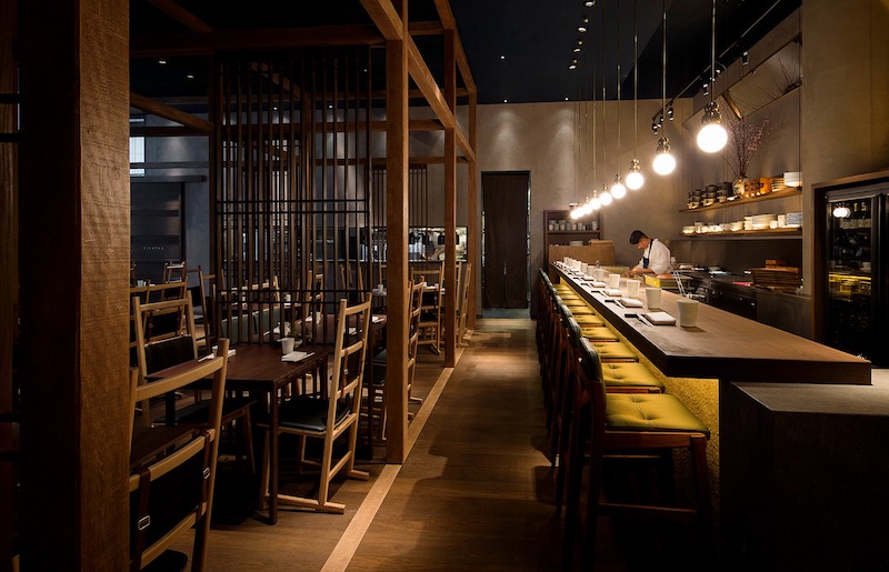 Nội thất trong nhà hàng Nhật Bản phong cách Izakaya sử dụng gỗ thô, lam gỗ, và ghế cao quầy bar, gợi nét mộc mạc nhưng năng động 