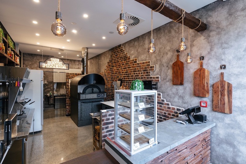 Không gian pizza truyền thống chú trọng sự ấm cúng với gỗ tối màu, ánh sáng vàng và chi tiết decor cổ điển, mang lại trải nghiệm ăn uống gần gũi, thân thuộc 