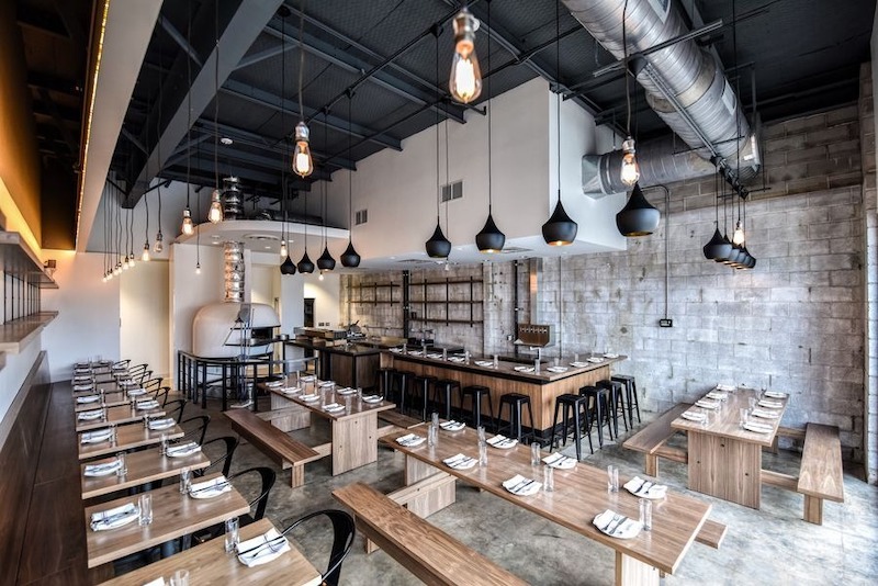 Tông màu trung tính, ánh sáng tập trung và chi tiết cơ khí lộ thiên giúp không gian quán pizza công nghiệp vừa nổi bật, vừa giữ được sự thoáng đãng, rộng rãi