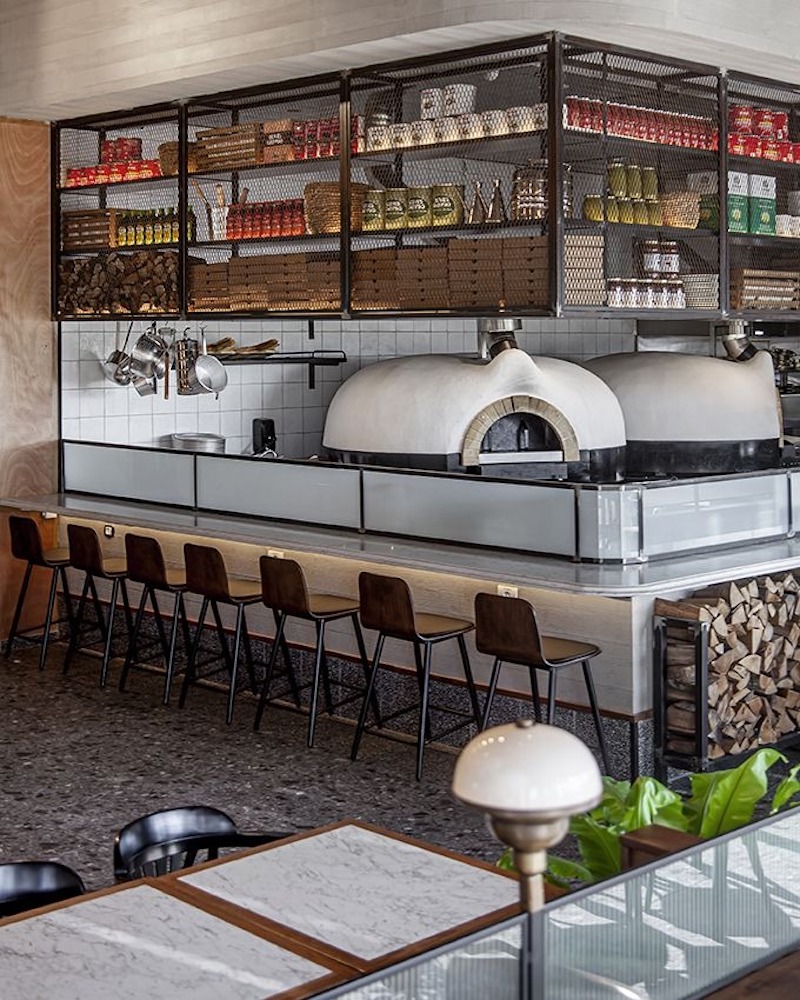 Bếp mở hoặc quầy bar hiện đại giúp khách quan sát quy trình làm pizza trực tiếp, vừa tăng trải nghiệm vừa tạo điểm nhấn cho không gian