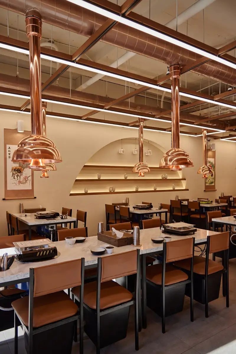 Ánh sáng trong quán lẩu nướng thường được xử lý ấm và đủ sáng, tạo không khí sôi động nhưng không gây cảm giác ngột ngạt 