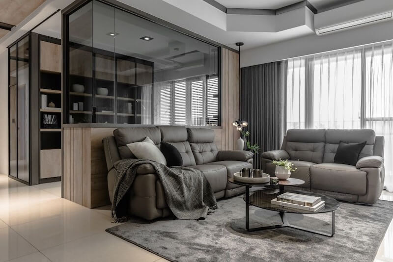 Không gian phòng khách hiện đại với nội thất được đặt riêng gồm ghế sofa xám, bàn trà tối giản và kệ sách gỗ kính, tạo cảm giác sang trọng và tinh tế