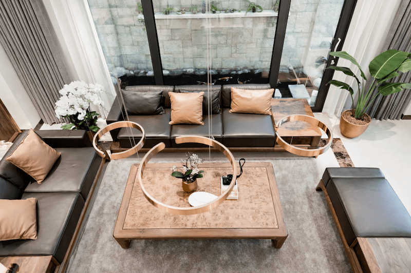 Phòng khách với bố cục mở, sofa da gam trung tính kết hợp bàn trà gỗ và hệ đèn thả kim loại tạo điểm nhấn tinh tế