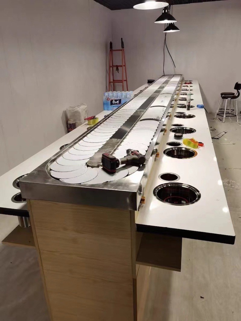 Hình ảnh thực tế thi công lẩu băng chuyền – Sự kết hợp giữa công nghệ vận hành tự động và thiết kế nội thất hiện đại đến từng chi tiết từ mặt đá, khung inox đến hệ thống điện âm bàn