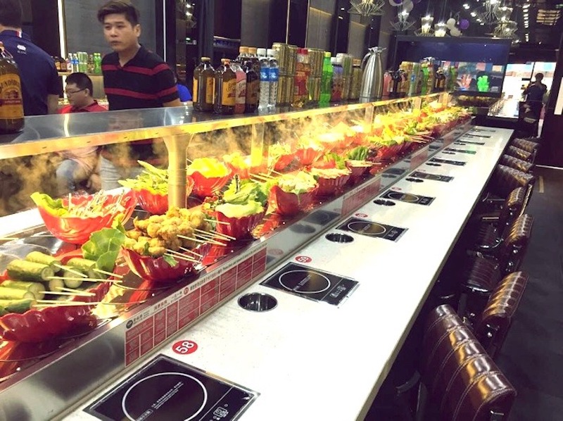 Hệ thống băng chuyền trong nhà hàng lẩu băng chuyền bố trí chữ U hợp lý, giúp khách dễ dàng tiếp cận món ăn và giữ lối đi thông thoáng 