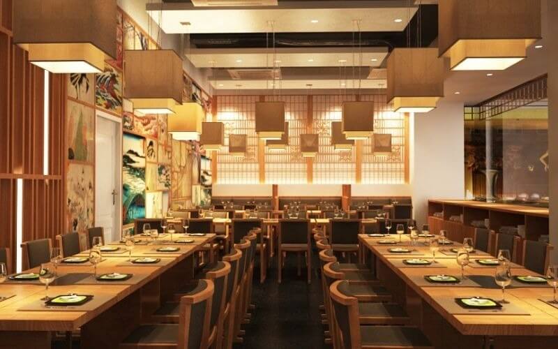 Thiết kế ánh sáng nhà hàng Sushi tinh tế với hệ thống đèn thả khối vuông hiện đại, kết hợp vách ngăn ánh sáng xuyên thấu và đèn âm trần giúp không gian ẩm thực ấm cúng