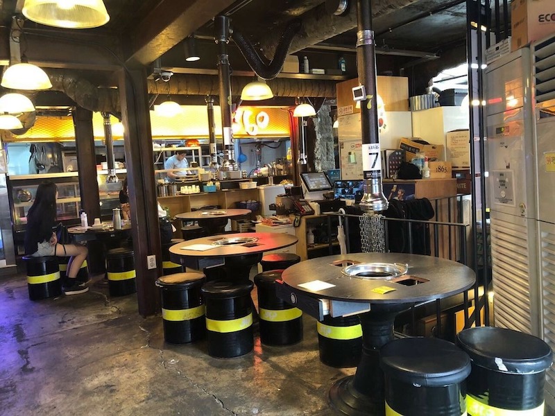 Kết hợp ánh sáng ấm áp, đèn dây LED và vật liệu thô mộc giúp quán nướng thùng phuy vừa bụi bặm vừa ấm cúng, tăng trải nghiệm khách hàng