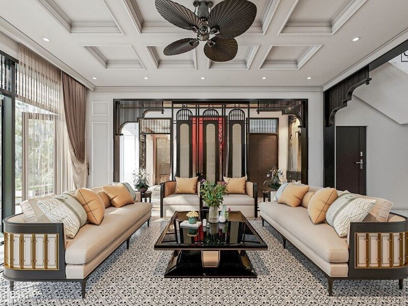 Không gian phòng khách phong cách Indochine hiện đại với nền gạch bông họa tiết cổ điển, bộ sofa đôi bọc nệm màu kem viền gỗ đen sang trọng và quạt trần cánh lá độc đáo