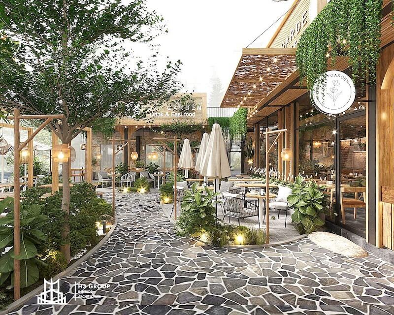 Thiết kế quán cafe theo phong cách Đà Lạt với không gian sân vườn lãng mạn, bàn ghế gỗ mộc, cây xanh và đèn ấm áp, tạo cảm giác gần gũi với thiên nhiên và thư thái