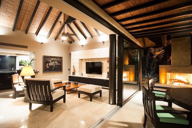 Không gian phòng khách kết nối trong - ngoài qua cửa kính trượt rộng, trần nan tre và ánh sáng lửa ấm, mang đến cảm giác nghỉ dưỡng sang trọng, thư thái, gần gũi thiên nhiên