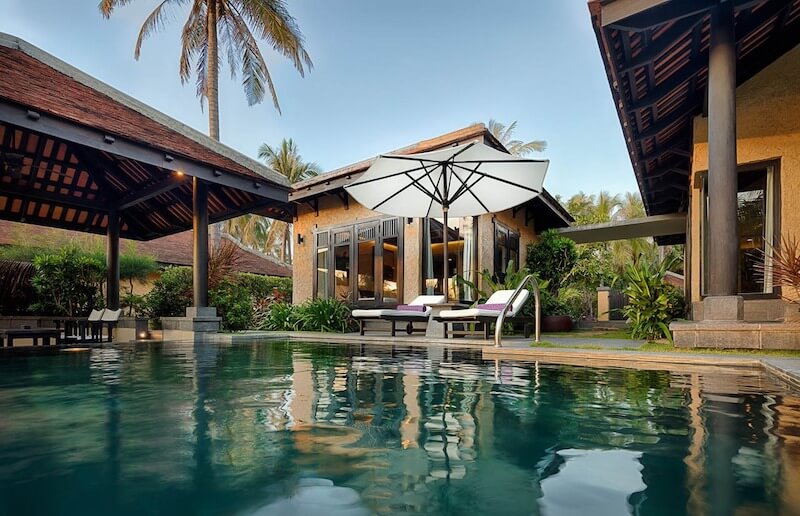 Không gian sinh hoạt ngoài trời với hồ bơi trung tâm, mái ngói dốc truyền thống, vật liệu đá – gỗ tự nhiên, mở rộng kết nối với cảnh quan nhiệt đới